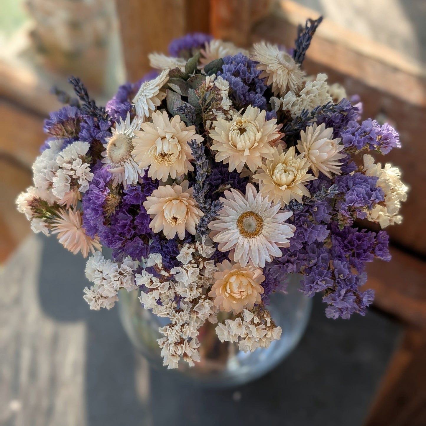 Bouquet of dried flowers in a clear vase on a wooden surface